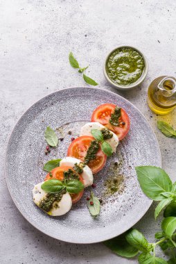 Fesleğenli, pesto soslu ve zeytinyağlı mozzarella ile domates. Yüksek kalite fotoğraf