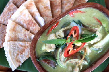 Thai green curry chicken with roti in wood bowl container,close up food green curry Muslim food