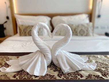 Aşk ve misafirperverliği simgeleyen, lüks bir otel odasındaki bir yatakta kalp şeklinde düzenlenmiş romantik kuğu havlusu sanatı geçmişi bulanıklaştırıyor.. 
