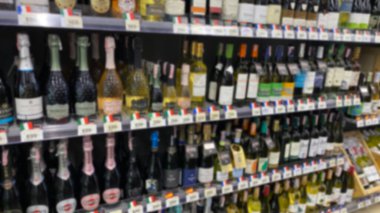 Süpermarkette rafta şarap şişesinin bulanık görüntüsü. Markette şarap ve içki açığı var, insan yok..