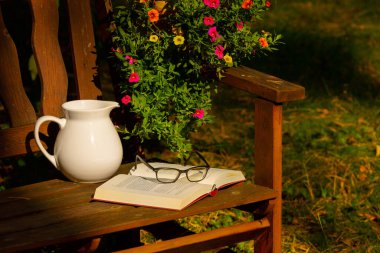 Gartenbank Brille Buch Milchkrug Abendlicht, Nachmittag, Ruhestand Hochformat, stille einsamkeit lndliches Leben, senioren, seniorenheim, senioreneinrichtung, buch leihen Pension rentner Nachmittag Abendlicht stimmung stimmungsvoll eigenheim Freizeit