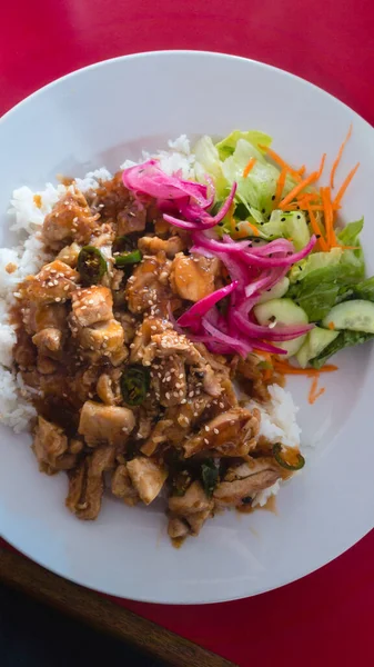 Chicken teriyaki flat-lay shot with vegetables and white steamed rice. Topped with sesame seeds and pickled red onion.