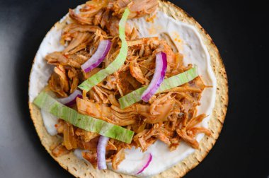 Üzerine doğranmış tavuk tinga tinga tinga de pollo, marul ve soğan konmuş mısır. Acı biber ve domatesle yapılan lezzetli Meksika yemekleri. Siyah bir tabakta servis edilmiş. Düz yatıyordu.