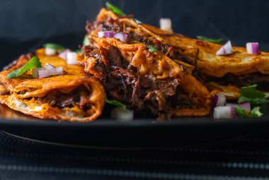 Siyah bir tabakta istiflenmiş 3 gevrek, sulu biftek birria taco. Tijuana, Meksika 'da inanılmaz Meksika yemeklerinin iştah açıcı düzeni..