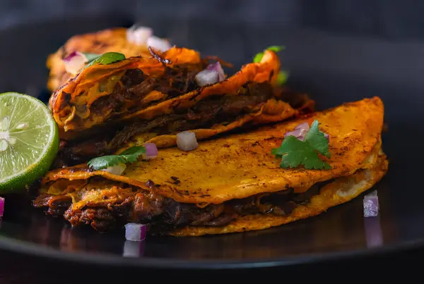 Siyah bir tabakta istiflenmiş 3 gevrek, sulu biftek birria taco. Tijuana, Meksika 'da inanılmaz Meksika yemeklerinin iştah açıcı düzeni..