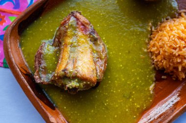 Meksika yemeği. Yeşil domates soslu tavşan, Meksika kırmızı pilavı ve kilden siyah fasulye. Hepsi geleneksel Meksika kil tabaklarında servis ediliyor..