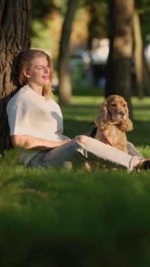 Genç Kadın Şehir Parkı 'ndaki çimlerde İngiliz Cocker Spaniel Köpeğiyle Oynuyor ve Eğleniyor. Evcil hayvanıyla gezen Çekici Kız