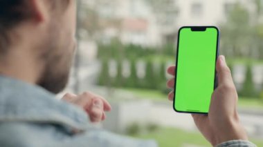 Dışarıdaki Adam Yeşil Model Ekran Telefonu Kullanıyor. Guy Smartphone 'da Kroma Anahtar Görüntüsü Üzerine Yazılar ve Dokunuşlar, Haberler İzliyor ve Smartphone' da Sosyal Medya aracılığıyla Parşömenler