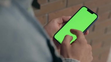 Dışarıdaki Adam Yeşil Model Ekran Telefonu Kullanıyor. Guy Smartphone 'da Kroma Anahtar Görüntüsü Üzerine Yazılar ve Dokunuşlar, Haberler İzliyor ve Smartphone' da Sosyal Medya aracılığıyla Parşömenler 