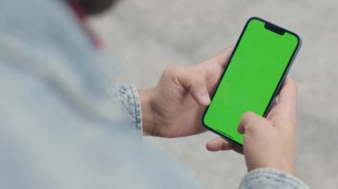 Dışarıdaki Adam Yeşil Model Ekran Telefonu Kullanıyor. Guy Smartphone 'da Kroma Anahtar Görüntüsü Üzerine Yazılar ve Dokunuşlar, Haberler İzliyor ve Smartphone' da Sosyal Medya aracılığıyla Parşömenler