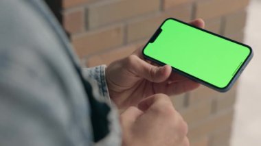 Dışarıdaki Adam Yatay Yeşil Model Telefon Kullanıyor. Guy Smartphone 'da Kroma Anahtar Görüntüsü Üzerine Yazılar ve Dokunuşlar, Haberler İzliyor ve Smartphone' da Sosyal Medya aracılığıyla Parşömenler