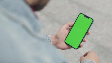Dışarıdaki Adam Yeşil Model Ekran Telefonu Kullanıyor. Guy Smartphone 'da Kroma Anahtar Görüntüsü Üzerine Yazılar ve Dokunuşlar, Haberler İzliyor ve Smartphone' da Sosyal Medya aracılığıyla Parşömenler
