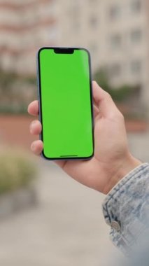 Şehrin arka planında, erkeklerin elinde dikey yeşil ekranlı telefonu kapat. Adam dışarıda Smartphone kullanıyor, Krom Anahtar Ekranında Parşömenler ve Dokunuşlar. Dikey Video