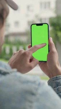 Dışarıdaki Adam Yeşil Model Ekran Telefonu Kullanıyor. Guy Scrolls ve Touches on Chroma Key Explay, News and Scrolls aracılığıyla Smartphone. Dikey Video