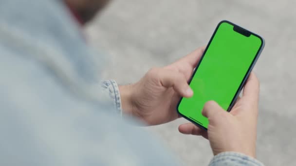 Homem Usando Verde Mock Screen Phone Livre Guy Scrolls Toques — Vídeo de Stock