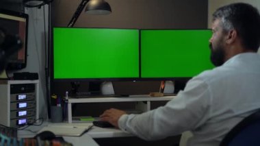 İnsan Tüccarı veya İşadamı Yeşil Ekran Modifiye İki Monitörlü Masaüstü Bilgisayarında Çalışıyor