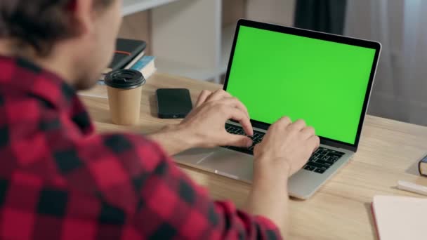 若い男は仕事のための緑のモックアップ スクリーンが付いているラップトップを使用しますまたは居心地のよい家のオフィスで勉強します ノートブックディスプレイのクロマキー — ストック動画