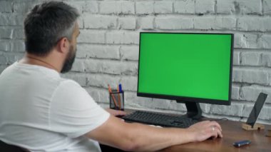 Yeşil Mock Up ekranlı, Masaüstü Bilgisayarı 'nda çalışan sakallı orta yaşlı adam. Beyaz Tuğla Duvarlı Modern Ofis