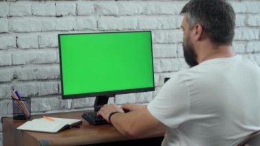 Yeşil Mock Up ekranlı, Masaüstü Bilgisayarı 'nda çalışan sakallı orta yaşlı adam. Beyaz Tuğla Duvarlı Modern Ofis