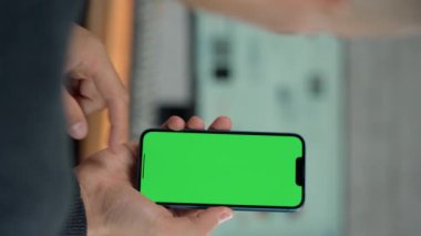 Telefonun Erkek Ellerinde Yeşil Ekran Modeli ile Kapanışı. Adam İş Yeri 'nde Bilgisayarın Yakınındaki Telefonu Kullanıyor