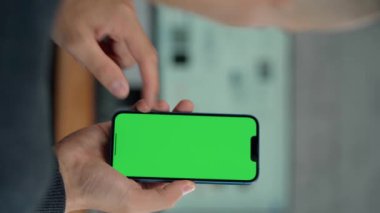 Telefonun Erkek Ellerinde Yeşil Ekran Modeli ile Kapanışı. Adam İş Yeri 'nde Bilgisayarın Yakınındaki Telefonu Kullanıyor