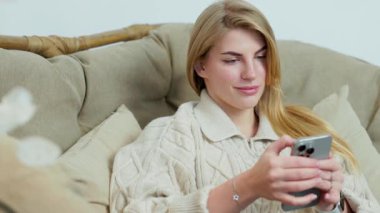 Sınıfta oturan akıllı telefonlu tatlı genç bir kadının portresi. Kız Telefonla Sosyal Medya aracılığıyla Videolar ve Parşömenler İzliyor