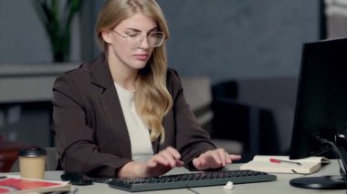 Masaüstü bilgisayarında çalışan gözlüklü bir iş kadını. İnternetteki İnternet ve Araştırma İşletmelerini İzleyen Kadın