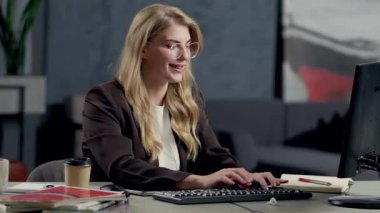 Ofiste Bilgisayarda Çalışırken Gülümseyen ve Konuşan Kadın