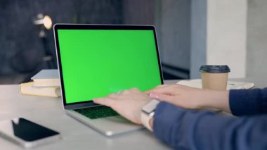 Yeşil ekranlı dizüstü bilgisayarla çalışan serbest çalışan birinin yakın çekimi. Chroma Anahtarı Dizüstü bilgisayarı. Bilgisayarda İzleme Defterini Kullanan Kadın Web sitesinde Kaydırıyor