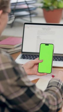 Dikey Yeşil Ekran ile Cep Telefonu Kullanan ve Not Defterine Bir Şey Yazan Genç Kadın
