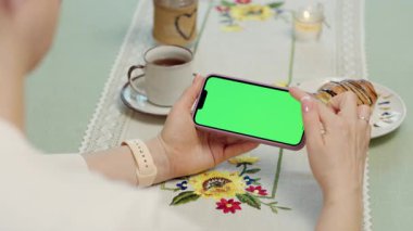 Kadın Ellerinde Yeşil Model Ekranlı Cep Telefonu 'nun Yakın Çekimi. Smartphone 'da Chroma Key Ekranı. Kafe 'de Dinlenen Kadın Akıllı Telefon Kullanıyor