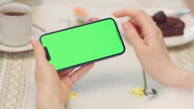 Kadın Ellerinde Yeşil Model Ekranlı Cep Telefonu 'nun Yakın Çekimi. Kafede dinlenirken akıllı telefon kullanan, çay içen ve tatlı yiyen bir kadın.