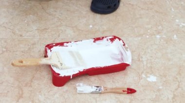 Duvardaki boya kutusuna beyaz plastik boya dökülüyor.