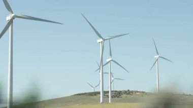 Wind generators spinning in operation viewed from a moving car. Travel