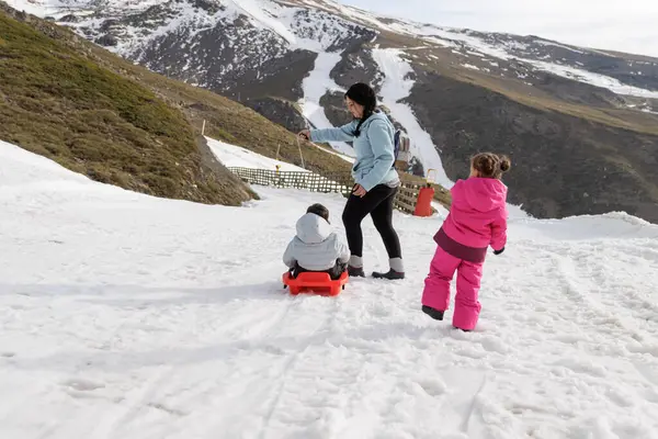 Family playing in the snow with a sled, Granada