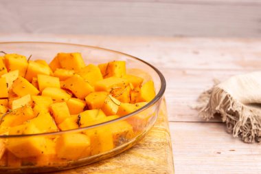 Evde baharat ve zeytinyağıyla bir kasede doğranmış balkabağı parçaları.