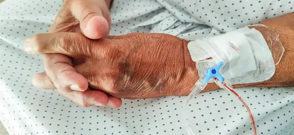 Elderly hands with osteoarthritis and venous catheter in the hospital