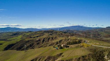 Tepelerinin karakteristik renkleriyle Toskana kırsalının panoramik manzarası.