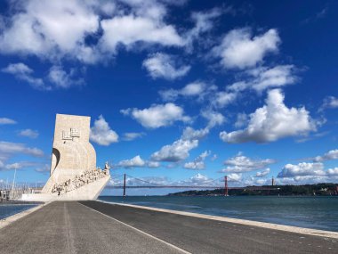 Padrao dos Descobrimentos ile boş Tagus Nehri kıyısı manzarası Keşifler Anıtı ve Lizbon Nehri üzerindeki 25 Nisan Köprüsü.