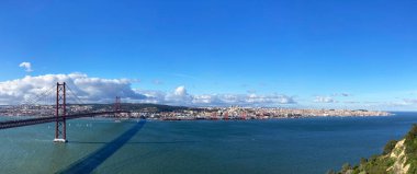 Lizbon 'un panoramik manzarası ve 25 Nisan' da Portekiz 'in Almada kentindeki Tagus nehri üzerindeki asma köprü manzarası.