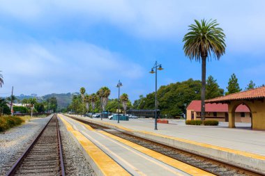 Santa Barbara istasyonunda, palmiye ağaçları ve açık mavi gökyüzü ile çevrili uzun, boş bir tren yolu..