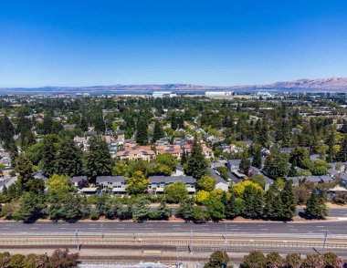 Mountain View, California 'daki Whisman İstasyonu' nun banliyö bölgesinin panoramik hava aracı görüntüsü. Demiryolu rayları, San Francisco Körfezi ve dağlar..