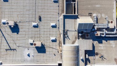 Havalandırma havalandırması ve havalandırma havalandırması olan düz, ticari bir çatı manzarası. Çatıda son zamanlarda havalandırma deliğinde onarım izleri var..