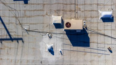 Havalandırma havalandırması ve havalandırma havalandırması olan düz, ticari bir çatı manzarası. Çatıda son zamanlarda havalandırma deliğinde onarım izleri var..