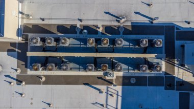 Havalandırma sistemleri, boruları ve yapısal elementleri olan düz bir çatı manzarası..