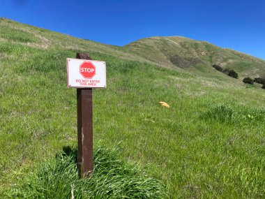 Dur, Bu Alan uyarı levhasını Girme Çimenli bir yamaçta duruyor.