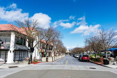 Los Altos şehir merkezindeki eyalet caddesi bir tarafta dükkanlar ve restoranlar diğer tarafta park edilmiş araçlar, çıplak ağaçlar ve açık gökyüzü - Los Altos, California, ABD - 2 Mart 2025