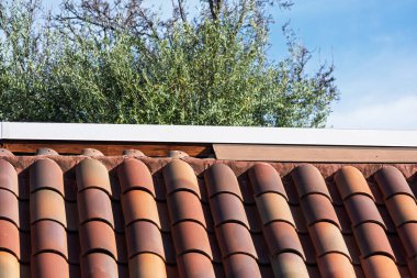 Beyaz fasya tahtasının altındaki terracotta çatı kiremitleri, açıkta duran ahşap kirişlerle kayıp bir metal kanat bölümünü ortaya çıkarıyor..