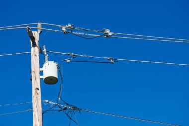Tahta bir direğe monte edilmiş elektrik trafosu elektrik kablolarına ve izolatörlere bağlanıyor...