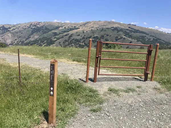 Coyote Gölü 'ndeki Ojo de Agua Yolu' nun girişindeki metal kapı ve ahşap işaret levhası Harvey Bear Ranch County Park, ABD - 4 Mayıs 2025